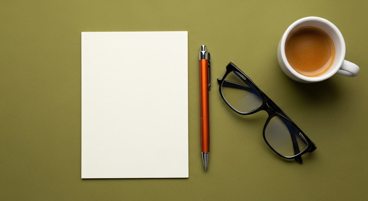 Paper, pen and glasses on a green table